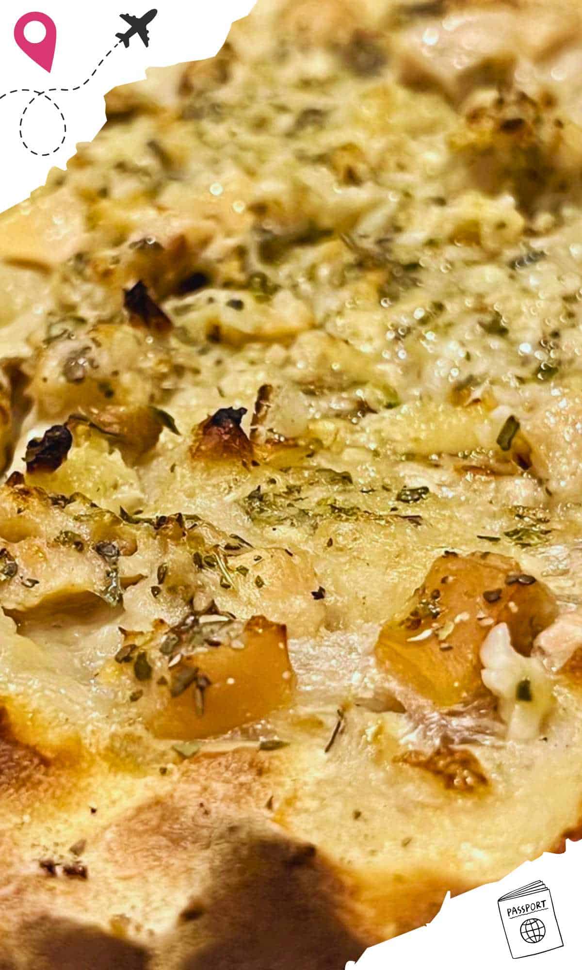 A close up of clams, cheese, and herbs on a pizza with creamy sauce.