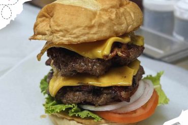 Juicy double beef cheeseburger with cheddar, fresh lettuce, tomato, onions, and toasted bun, perfect for burger lovers and fast food enthusiasts.