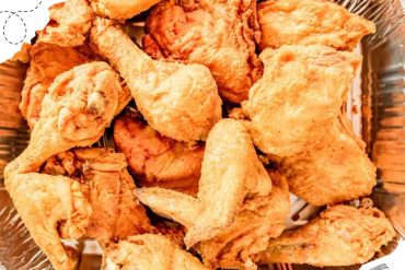 Crispy fried chicken drumsticks and wings in a metal basket, showcasing delicious Southern-style comfort food perfect for travel food experiences.