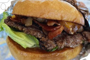 Savory burger with grilled beef patty, lettuce, bacon, and caramelized onions in a toasted bun, featuring fresh ingredients and rich flavors, perfect for a hearty meal or casual dining experience.