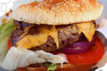 Beef cheeseburger with melted cheddar cheese, lettuce, tomato, onion, and sesame seed bun, close-up view for American fast food cuisine, travel, and food tourism images, vibrant and appetizing.