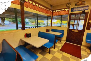 Strawberry milkshake diner interior cozy seating with blue booths and large windows showcasing street view for travel dining experiences.