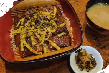 BBQ eel rice bowl with yellow shredded egg and seaweed garnish, served with miso soup and pickled vegetables, showcasing authentic Japanese cuisine perfect for travel food experiences.