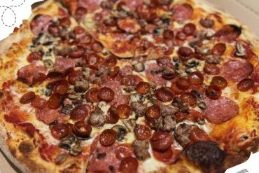 Freshly baked meat lovers pizza topped with pepperoni, sausage, and mushrooms, featuring a crispy golden crust and melted cheese, perfect for a delicious meal.