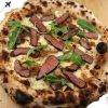 Juicy grilled steak on a gourmet pizza with arugula and caramelized onions, crispy crust, and melted cheese, perfect for food lovers and pizza enthusiasts.
