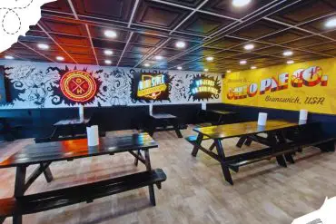 Vintage arcade bar with graffiti wall art and wooden picnic tables in Brunswick, USA.