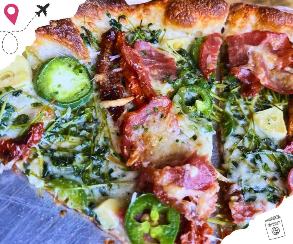 A close up of a slice of pizza with jalepenos and pepperoni.