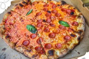 Thin-crust pepperoni pizza with fresh basil on a cardboard box, emphasizing delicious pizza delivery and takeaway experiences. Perfect for food lovers exploring travel and dining destinations.