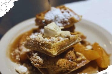 Fluffy apple pie dessert topped with vanilla ice cream and powdered sugar on a white plate, served with caramel sauce, perfect for travel food photography and dessert lovers.