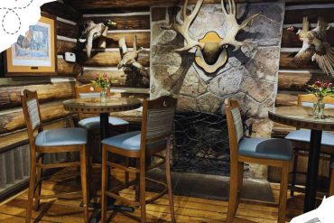 Rustic lodge interior with log walls and wildlife decor, including mounted antlers, ducks, and bird plaques, cozy seating with wood tables, perfect for a mountain or hunting lodge atmosphere, ideal for hunting or nature-themed travel destinations.