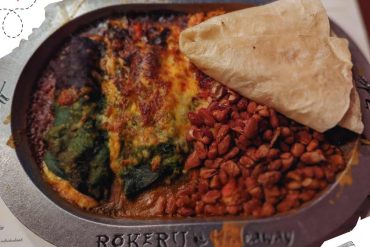 Baked lasagna with cheese, spinach, and tomato sauce served with a side of crispy refried beans and a flour tortilla in an American-style restaurant.
