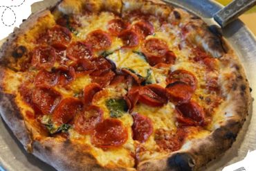 Freshly baked pepperoni pizza with melted cheese, crispy crust, and flavorful toppings, served on a round metal tray. Perfect for travel and global cuisine enthusiasts exploring food destinations.