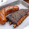 Grilled sausage and smoked pork ribs served on parchment paper for barbecue meal.