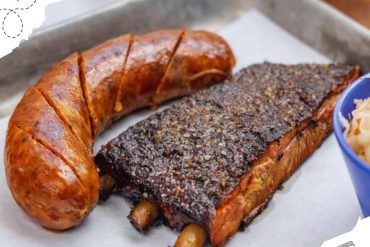 Grilled sausage and smoked pork ribs served on parchment paper for barbecue meal.
