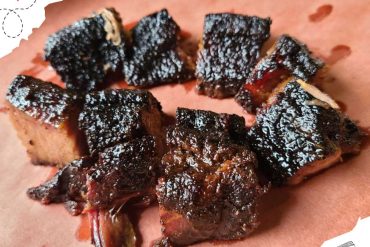 Smoked beef rib chunks with a dark, crispy bark, served on a sheet of parchment paper, showcasing delicious barbecue flavor. Perfect for meat lovers and BBQ enthusiasts seeking authentic grilled cuisine.