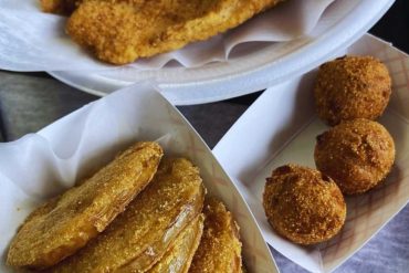 Crispy fried fish fillets with golden breading, served with breaded fried plantains and croquettes, ideal for authentic Caribbean cuisine experience.