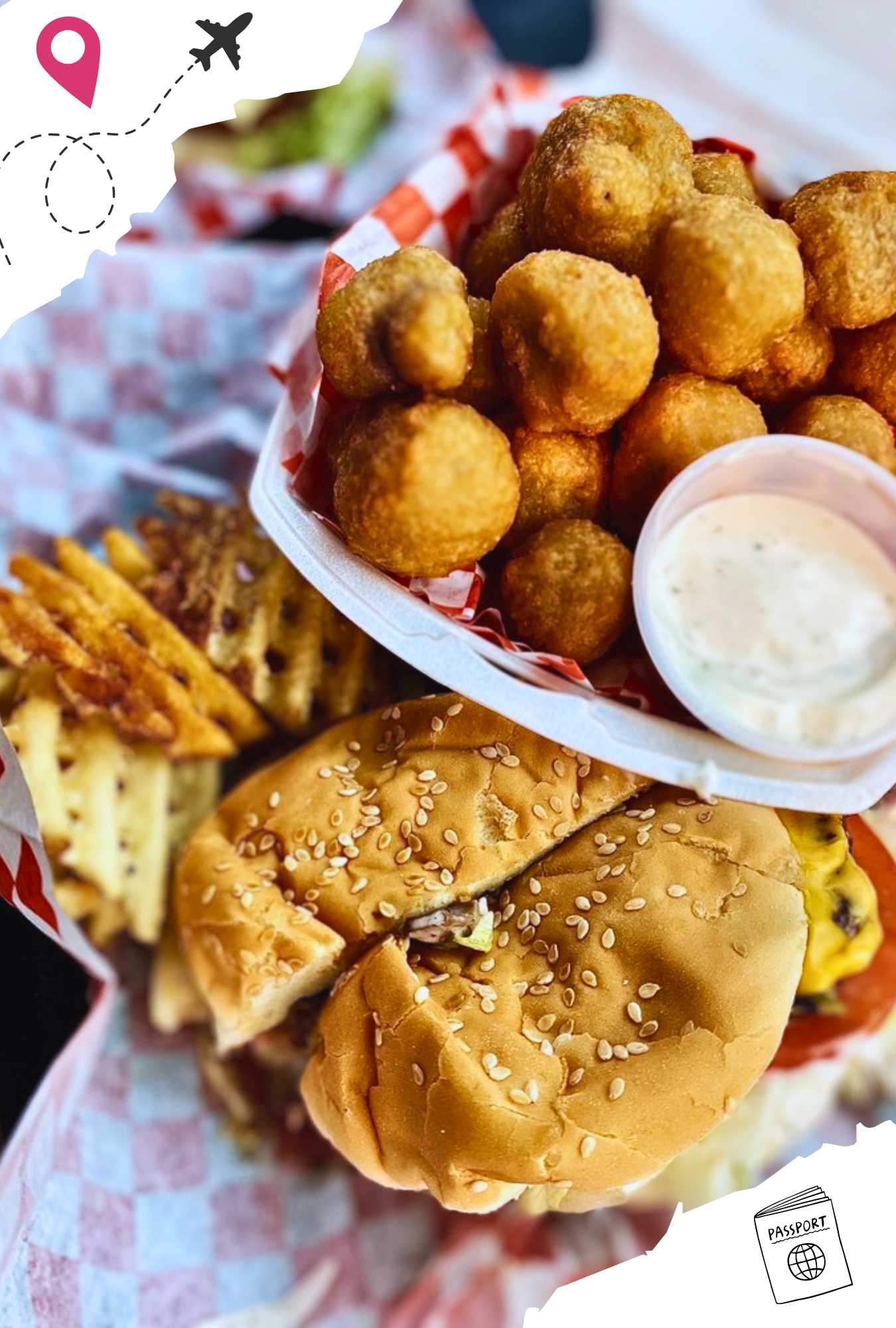 A cheeseburger sliced in half with a side of hush puppies and waffle fries.