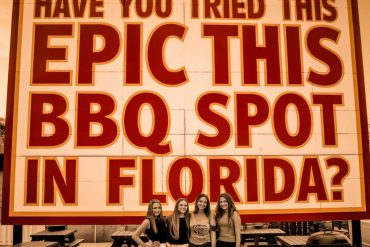 Epic BBQ spot in Florida sign with four smiling women enjoying a meal at an outdoor patio. Perfect for travel, food, and Florida vacation SEO.
