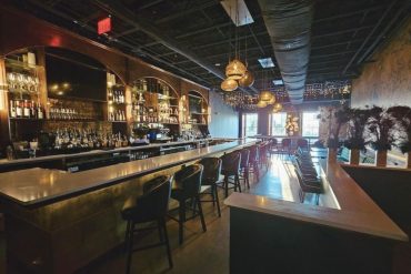 Luxurious bar interior with a sleek white countertop, modern ambient lighting, and stylish seating area, perfect for upscale nightlife experiences at top destinations.