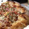 Crispy stuffed pizza with melted cheese, fresh herbs, and savory toppings on a wooden table for authentic Italian pizza experience.