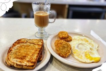Toasted bread with fried eggs and hash browns, along with a glass of coffee, served as a delicious breakfast at a local café. Perfect for travelers seeking a hearty meal during their adventures.