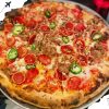 Hot and delicious pepperoni sausage pizza topped with sliced jalapenos and red chili flakes, served on a silver tray, perfect for travel and food lovers exploring renowned destinations worldwide.