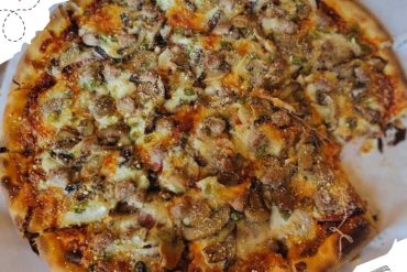 Fresh mushroom and cheese pizza topped with melted cheese and herbs, ready to serve at a pizzeria. Perfect for pizza lovers seeking delicious, savory Italian cuisine.