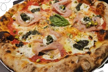 Fresh Italian pizza with prosciutto, basil, ricotta, pistachios, and black garlic on a rustic crust. Perfect for pizza lovers seeking authentic flavors and gourmet toppings.