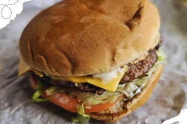 Fresh cheeseburger with lettuce, tomato, melted cheese, and a beef patty on a toasted bun, perfect for travelers exploring delicious local cuisine around the world.