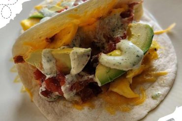 Savory breakfast taco with scrambled eggs, avocado, bacon, and creamy sauce on a soft tortilla, perfect for travel destinations and food adventures.