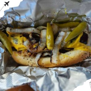 Golden grilled shrimp taco with roasted onions and pickled peppers wrapped in foil, showcasing delicious seafood cuisine.