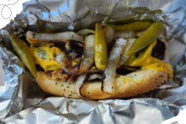 Golden grilled shrimp taco with roasted onions and pickled peppers wrapped in foil, showcasing delicious seafood cuisine.