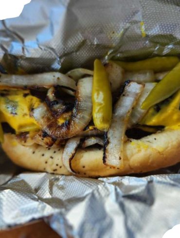 Golden grilled shrimp taco with roasted onions and pickled peppers wrapped in foil, showcasing delicious seafood cuisine.