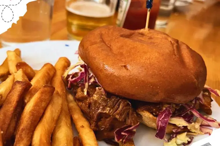 Burger with blue decorative toothpick stuck into it with a side of French fries.