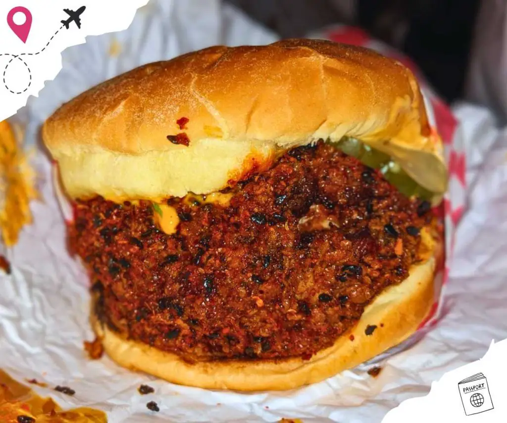 A burger with a very large portion of ground beef in red seasonings.