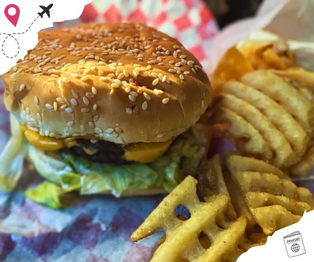 Cheeseburger with sesame seeds on the bun and waffle fries on the side.