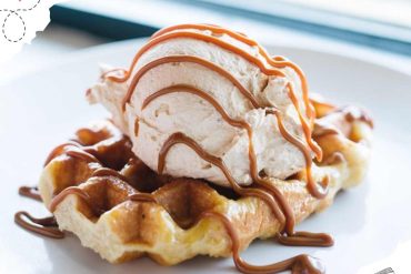 Sweet waffle topped with vanilla ice cream, caramel drizzle, and whipped cream, served as a delicious dessert or treat. Perfect for travel food lovers seeking sweet destinations.