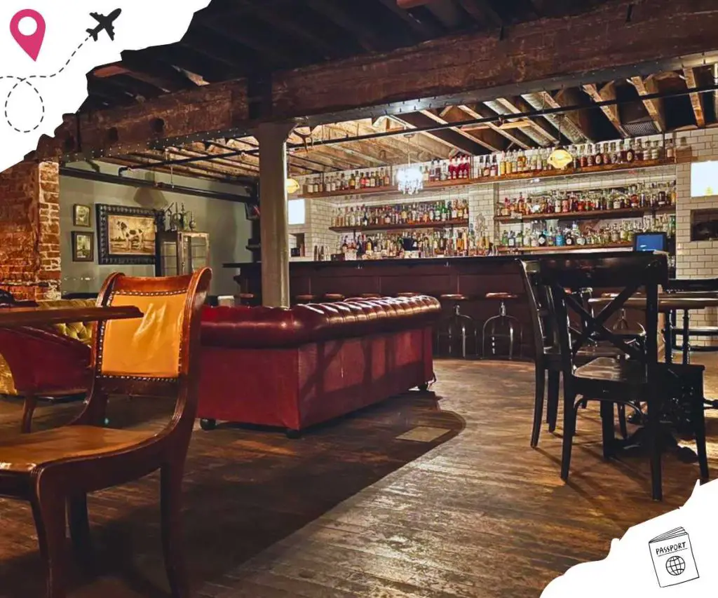 A scenic bar and lounge area with shelves of drinks, red sofas, tables and chairs.