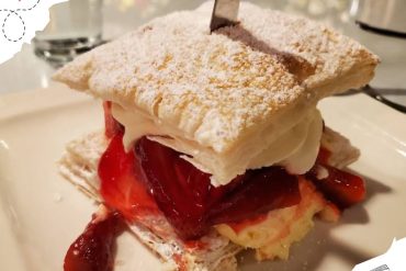 Fresh strawberry and cream mille-feuille dessert with powdered sugar for travel and culinary tourism.