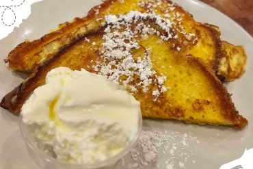 Golden French toast topped with powdered sugar and served with a side of whipped cream, perfect for breakfast or brunch. Enjoy this delicious, easy-to-make breakfast dish.