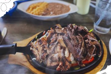 Juicy sizzling grilled steaks served on a hot cast iron skillet with fresh vegetables, perfect for travel food lovers exploring culinary destinations around the world.