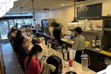 Premium ramen restaurant interior with diners enjoying meal, bustling casual dining atmosphere, urban setting for food lovers, modern decor, lively cafe scene, Asian cuisine experience, cozy restaurant ambiance, popular destination for food tourism.