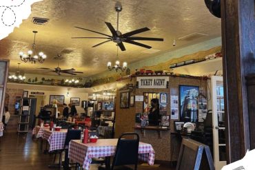Vintage restaurant interior with cozy dining area, checkered tablecloths, and ticket agent decor, perfect for travelers and dining enthusiasts seeking a nostalgic travel-themed atmosphere.