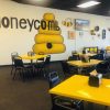 Honeycomb mural with bee artwork on dining room wall in honey-themed café, bright yellow tables and black chairs, cozy atmosphere, perfect for breakfast or casual meals.