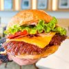 Juicy cheeseburger with lettuce, tomato, bacon, and melted cheddar in a toasted bun, perfect for travel food adventures at top destinations.