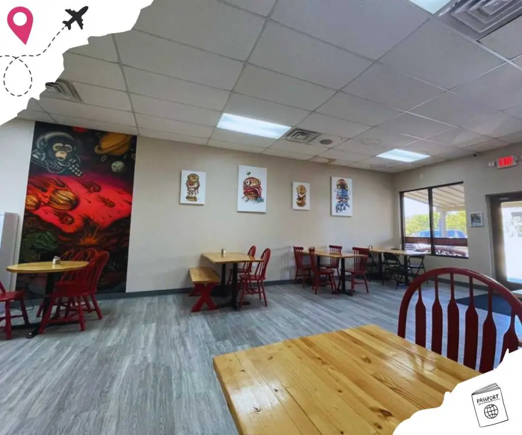 Colorful interior of a casual dining restaurant with wooden tables, red chairs, and wall art featuring astronaut and space-themed illustrations. Bright natural light from windows enhances the welcoming atmosphere.