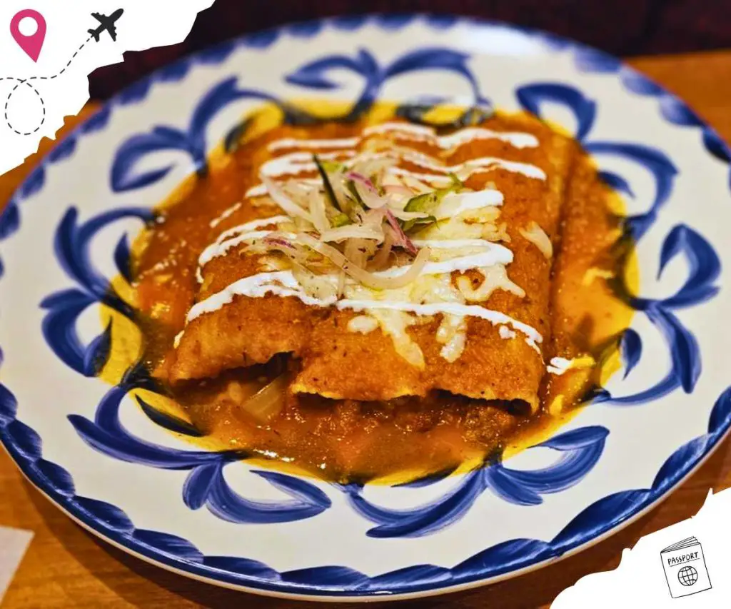 Two enchiladas topped with cheese and garnish on a blue and white decorated plate.