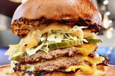 Juicy cheeseburger with lettuce, pickles, and melted cheese on a toasted bun at a restaurant, close-up image.