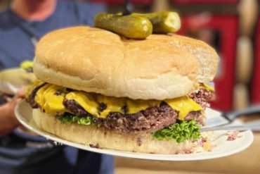 Juicy cheeseburger sub with pickles, lettuce, and melted cheese, served on a fresh sandwich bun. Ideal for food lovers exploring popular American cuisine and fresh deli sandwiches at top destinations.