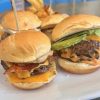 Crispy cheeseburger sliders with bacon and fresh lettuce on mini buns, served at a casual dining restaurant for a quick tasty meal.